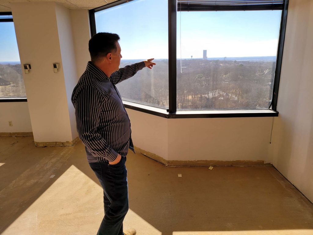 Greg Fritz pointing out studio window to a view of Colorado area